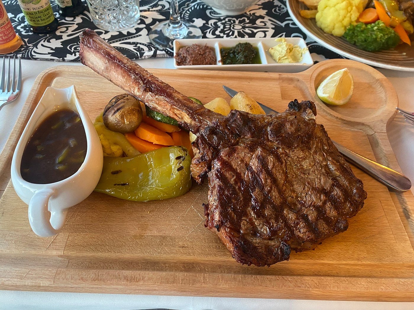 Tomahawk steak on wooden board with grilled vegetables